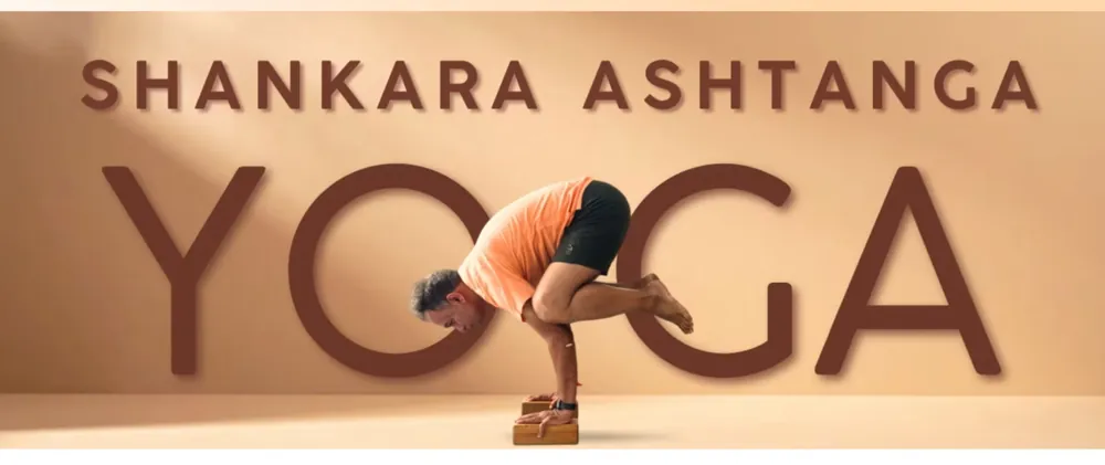 Yoga arm-balance practice in front of the Shankara Ashtanga Yoga studio lettering